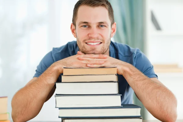 Estudante sorrindo apoiando-se em seus livros — Fotografia de Stock