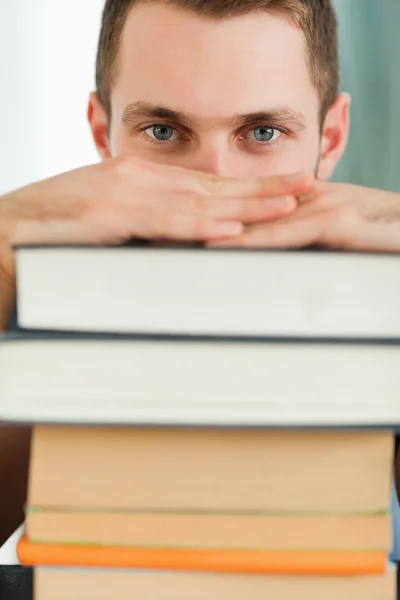 Primer plano del estudiante escondido detrás de un montón de libros — Foto de Stock
