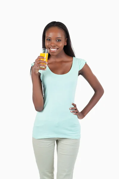Sorrindo jovem mulher tomando um gole de suco de laranja — Fotografia de Stock