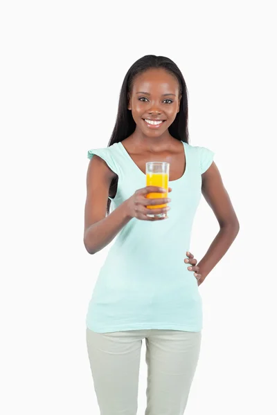 Sonriente joven hembra tomando un vaso de jugo de naranja — Foto de Stock