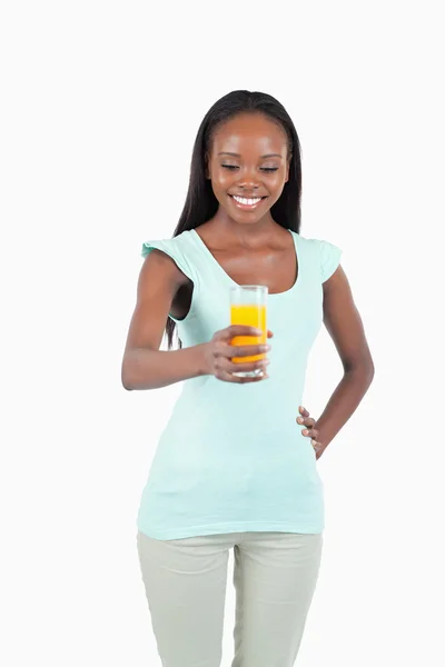 Χαμογελώντας νέα γυναίκα που κρατά ένα ποτήρι χυμό πορτοκαλιού — Φωτογραφία Αρχείου