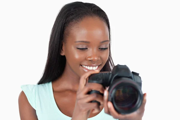 Lächelnde junge Fotografin mit Blick auf ihre Kamera — Stockfoto