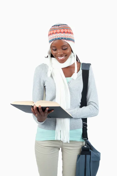 Smiling student with winter clothes reading — Stock Photo, Image