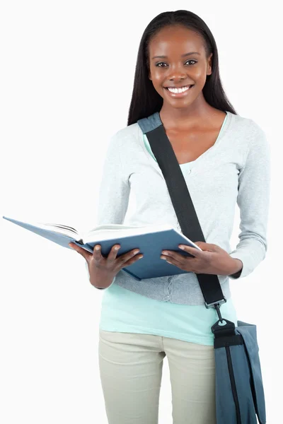 Χαμογελαστός νεαρός φοιτητής με τσάντα ανάγνωση στο βιβλίο της — Φωτογραφία Αρχείου
