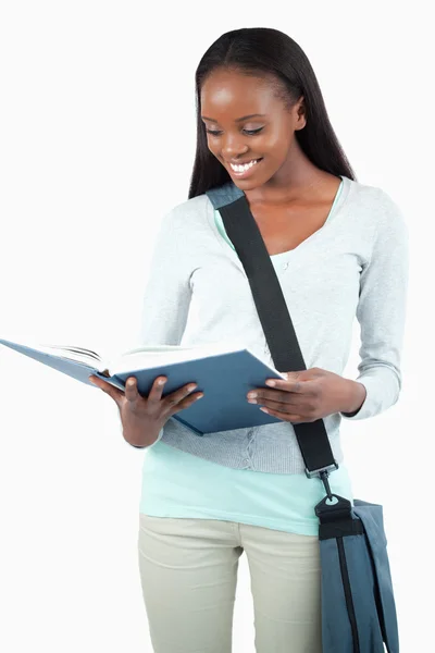 Smiling student with bag reading in her book — Stock Photo, Image
