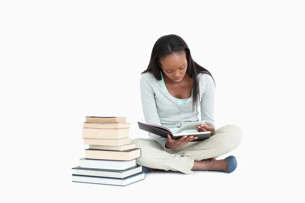 Young woman reading next to a stack of books — Stock Photo, Image