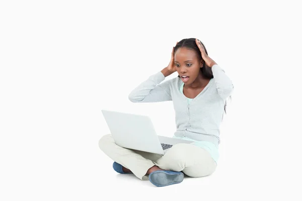 Jovem mulher no chão surpreendida por seu laptop — Fotografia de Stock