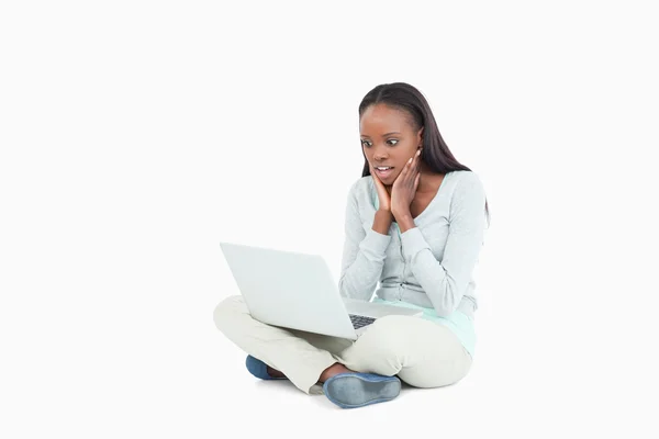 Young woman on the floor cannot believe whats on her screen — Stock Photo, Image