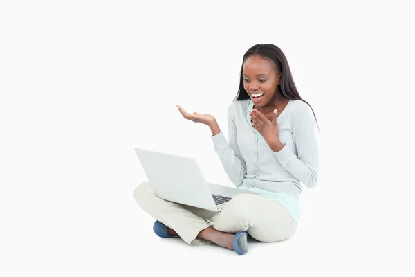 Frau sitzt auf dem Boden und blickt auf ihren Laptop — Stockfoto
