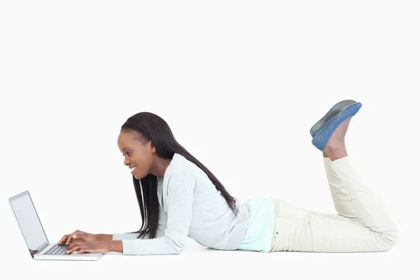 Vista lateral da mulher deitada no chão com seu laptop — Fotografia de Stock