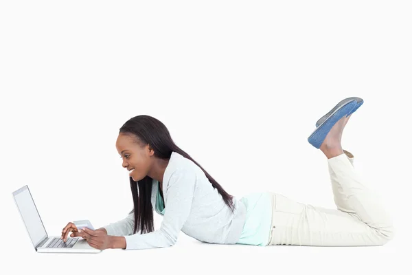 Sidovy av leende kvinna på golvet med sin laptop — Stockfoto
