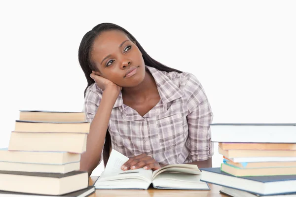 Jonge vrouw dagdromen naast stapel van boek — Stockfoto