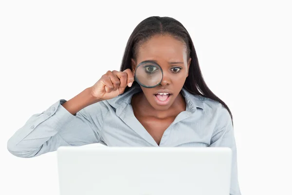 Affärskvinna med hjälp av ett förstoringsglas för att titta på hennes laptop — Stockfoto