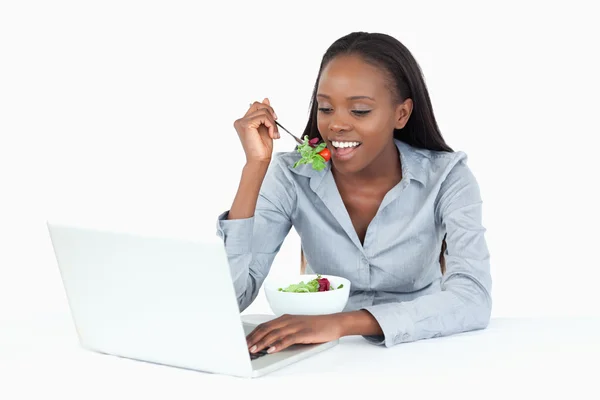 Kobieta pracuje z laptopa, a jedzenie sałatka — Zdjęcie stockowe