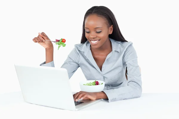 Young businesswoman working with a notebook while eating a salad — Stock Photo, Image