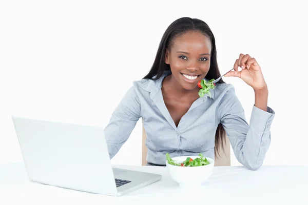 Cute businesswoman working with a notebook while eating a salad — Stock Photo, Image