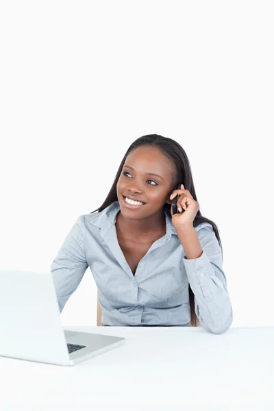 Porträtt av en kvinna att göra ett telefonsamtal medan du använder en bärbar dator — Stockfoto