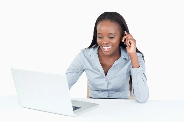 Bir dizüstü bilgisayar kullanırken telefonla iş kadını — Stok fotoğraf