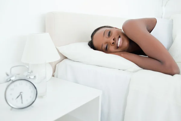 Woman waking up with her alarm clock — Stock Photo, Image