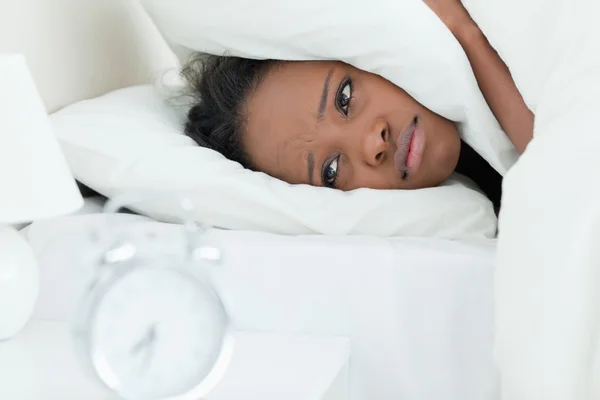 Trött kvinna som täcker öronen medan hennes väckarklocka ringer — Stockfoto