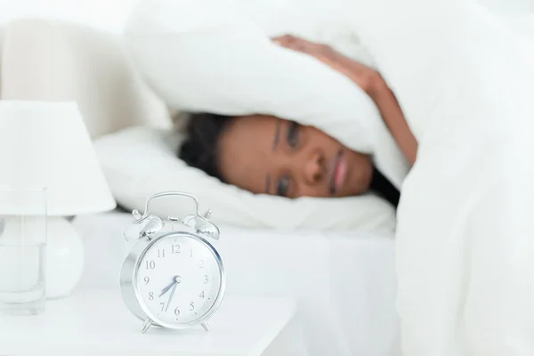 Young woman covering her ears while her alarm clock is ringing — Stock Photo, Image