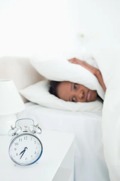 Porträt einer müden Frau, die ihre Ohren bedeckt, während ihr Wecker klingelt — Stockfoto