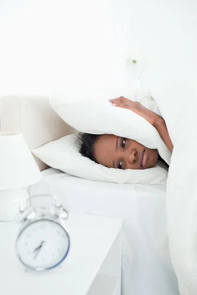 Porträt einer jungen Frau, die ihre Ohren bedeckt, während ihr Wecker klingelt — Stockfoto