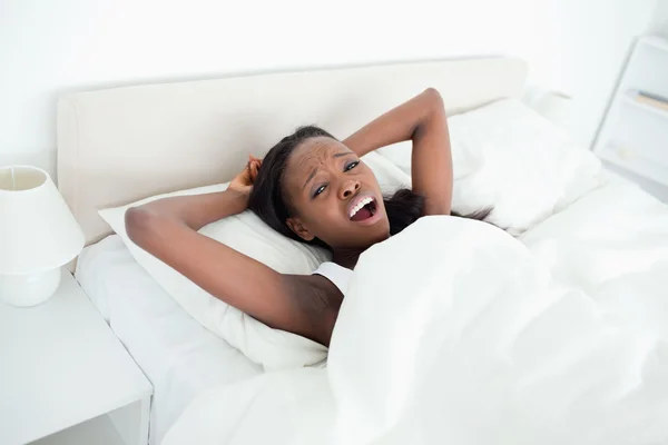Женщина зевает на своей кровати — стоковое фото