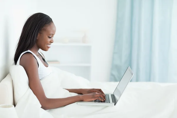 Uyumadan önce bir dizüstü bilgisayar kullanan genç kadın — Stok fotoğraf