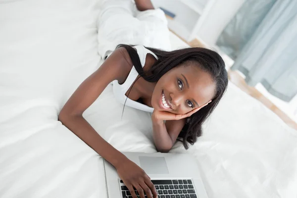 젊은 여자는 노트북을 사용 하 여 그녀의 배꼽에 누워 — 스톡 사진