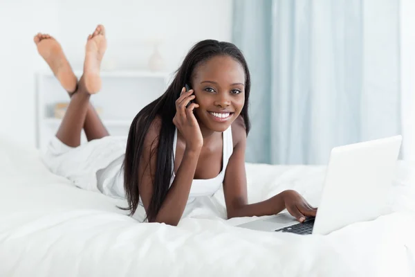 Mutlu bir kadın telefon görüşmesi yaparken bir dizüstü bilgisayar kullanarak — Stok fotoğraf