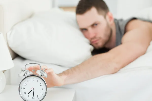 Homem infeliz desligando seu despertador — Fotografia de Stock