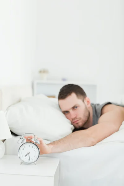 Portrait of a man being awakened by an alarm clock — Stock Photo, Image