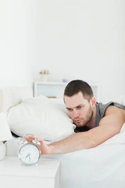 Portrait of a unhappy man being awakened by an alarm clock — Stock Photo, Image