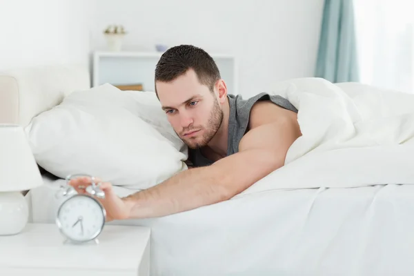 Tired man being awakened by an alarm clock — Stock Photo, Image