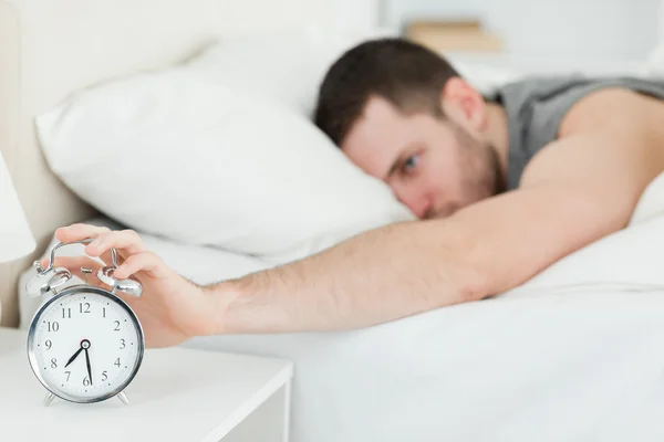 Hombre de cabello castaño siendo despertado por un despertador — Foto de Stock
