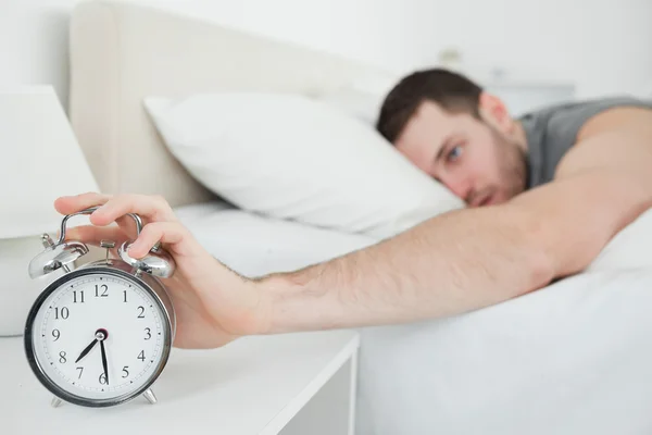 Young man being awakened by an alarm clock — Stock Photo, Image