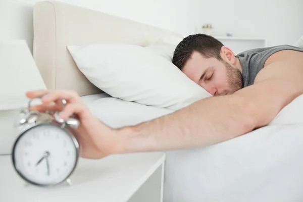 Dormir bonito homem sendo despertado por um despertador — Fotografia de Stock