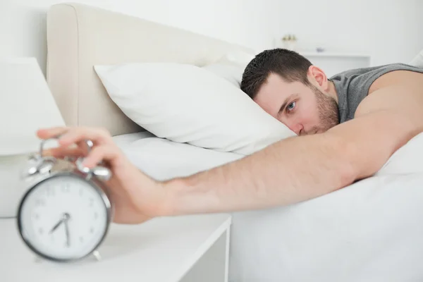 Sleeping attractive man being awakened by an alarm clock — Stock Photo, Image