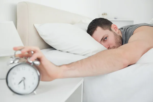 Attractive man being awakened by an alarm clock — Stock Photo, Image