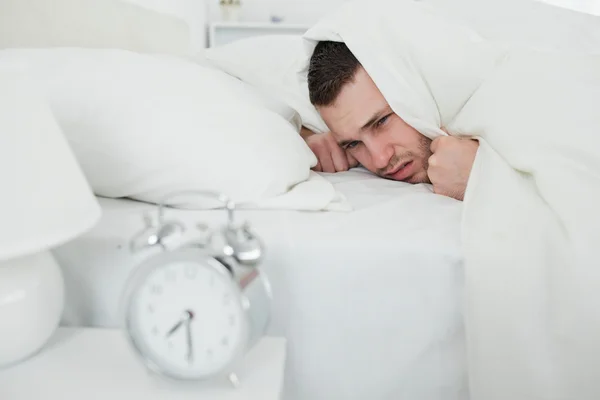 Man covering his ears while his alarm clock is ringing — Stock Photo, Image