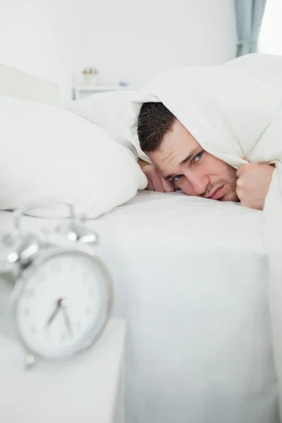 Portrait of a man covering his ears while his alarm clock is rin — Stock Photo, Image
