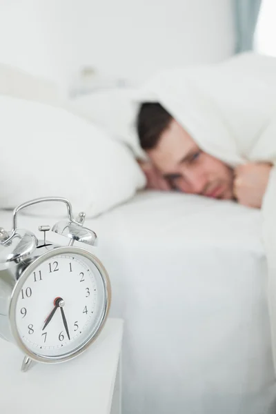 Портрет уставшего человека, закрывающего уши, пока его будильник — стоковое фото