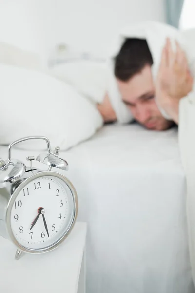 Portrait of a exhausted man covering his ears while his alarm cl — Stock Photo, Image
