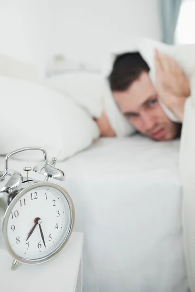 Portrait of a handsome man covering his ears while his alarm clo — Stock Photo, Image