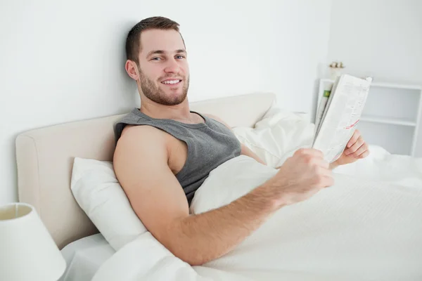 Gülümseyen genç adam bir gazete okuyor — Stok fotoğraf