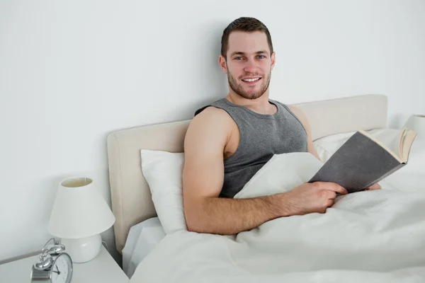 Smiling man reading a novel — Stock Photo, Image
