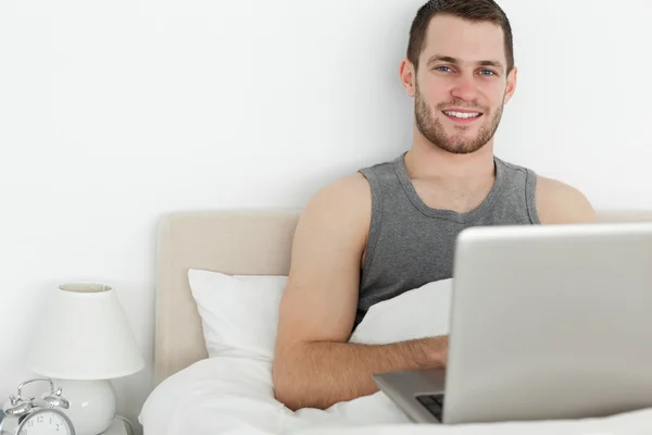 Yakışıklı bir adam bir dizüstü bilgisayar kullanarak — Stok fotoğraf