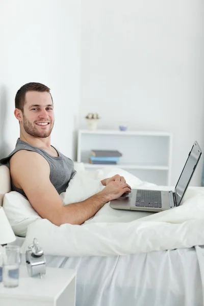 Bir dizüstü bilgisayar kullanarak gülümseyen bir adam portresi — Stok fotoğraf