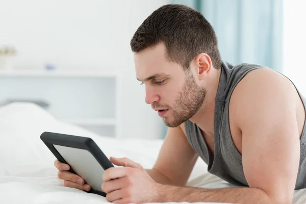 남자 그의 배꼽에 누워 있는 동안 태블릿 컴퓨터를 사용 하 여 — 스톡 사진